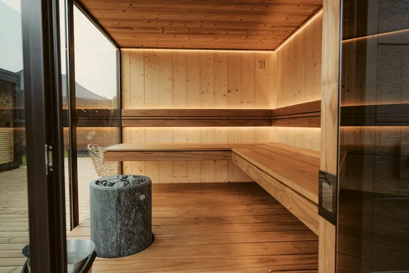 Sauna aus hellem Holz mit Steinofen